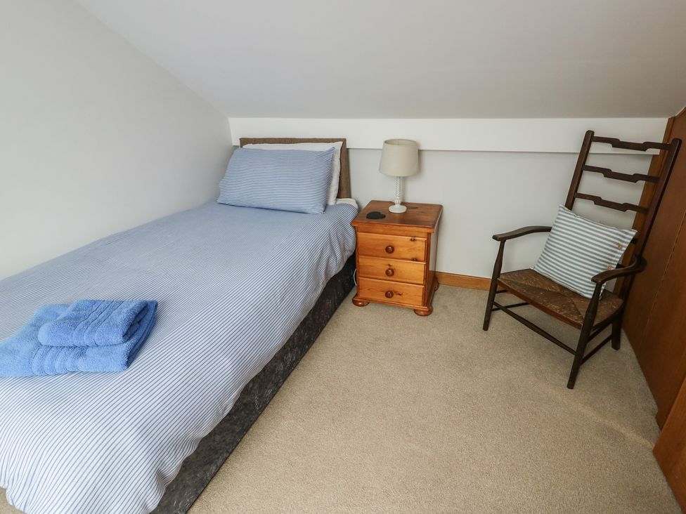 A bedroom with a bed and a chair at Yr Orsedd in Llanfaethlu