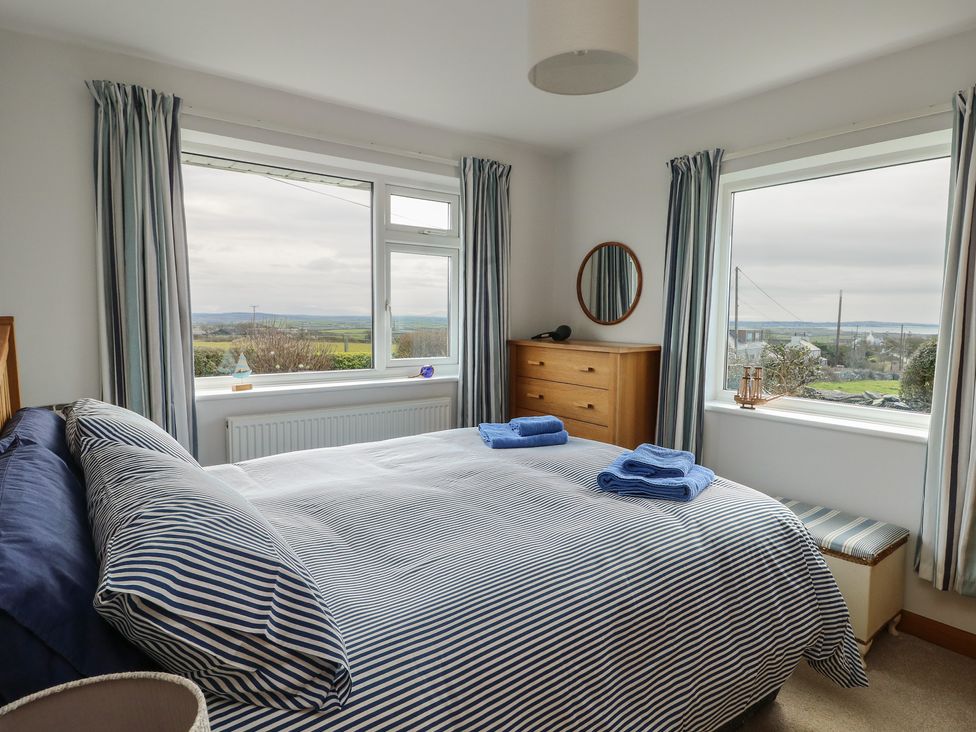 A bedroom with a bed and dresser at Yr Orsedd Llanfaethlu