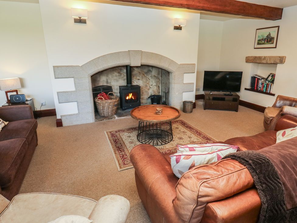 A living room with a stone fireplace and television at Shoebroad Barn in Todmorden