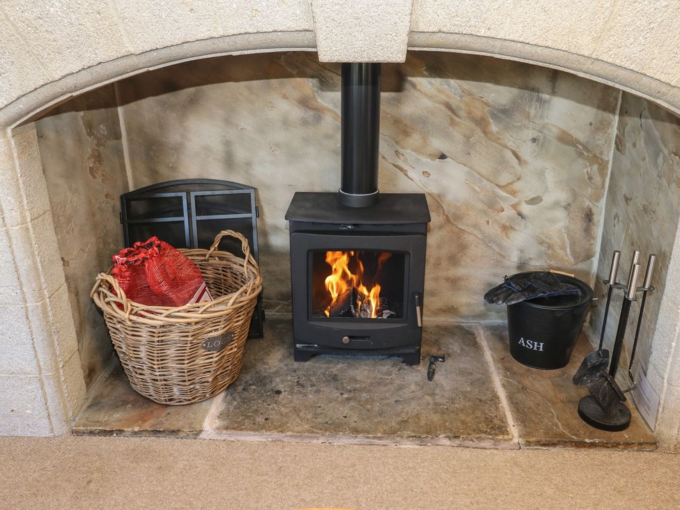A living room with a fireplace and log basket at Shoebroad Barn in Todmorden