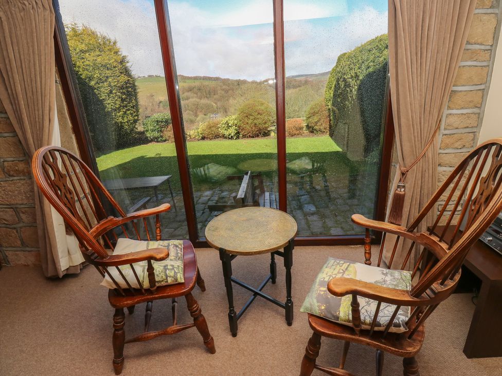 A seating area with two rocking chairs and a table overlooking a garden at Shoebroad Barn in Todmorden