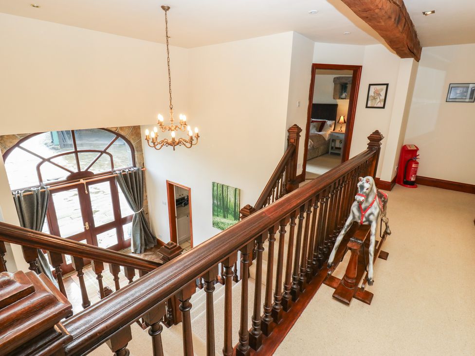 A hallway with a staircase and chandelier at Shoebroad Barn Todmorden