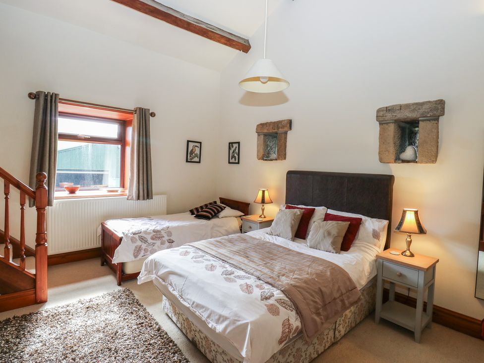 A bedroom with two beds and a staircase at Shoebroad Barn Todmorden