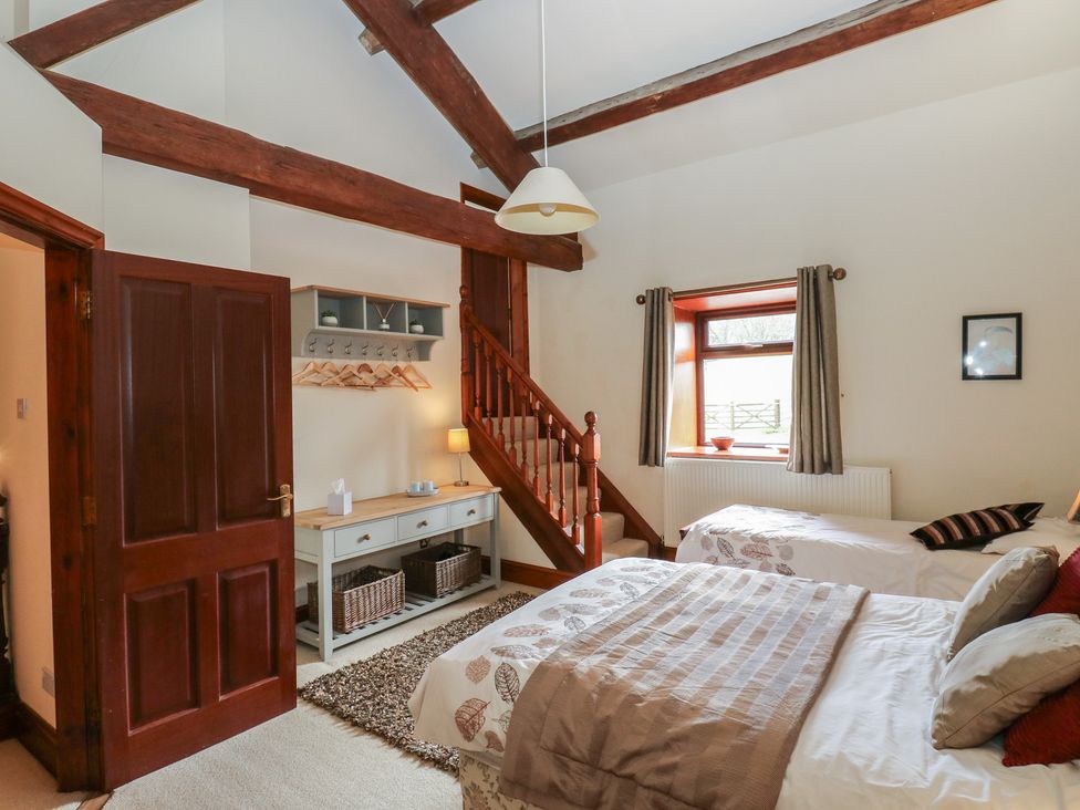 A bedroom with two beds and a staircase at Shoebroad Barn in Todmorden