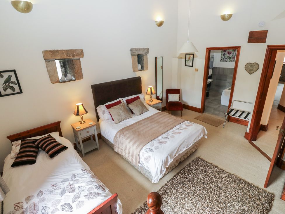 A bedroom with two beds and a side table at Shoebroad Barn in Todmorden