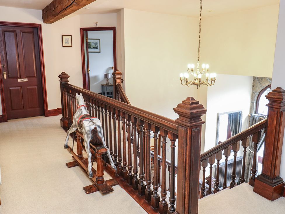 A hallway with a chandelier and a horse figurine at Shoebroad Barn in Todmorden