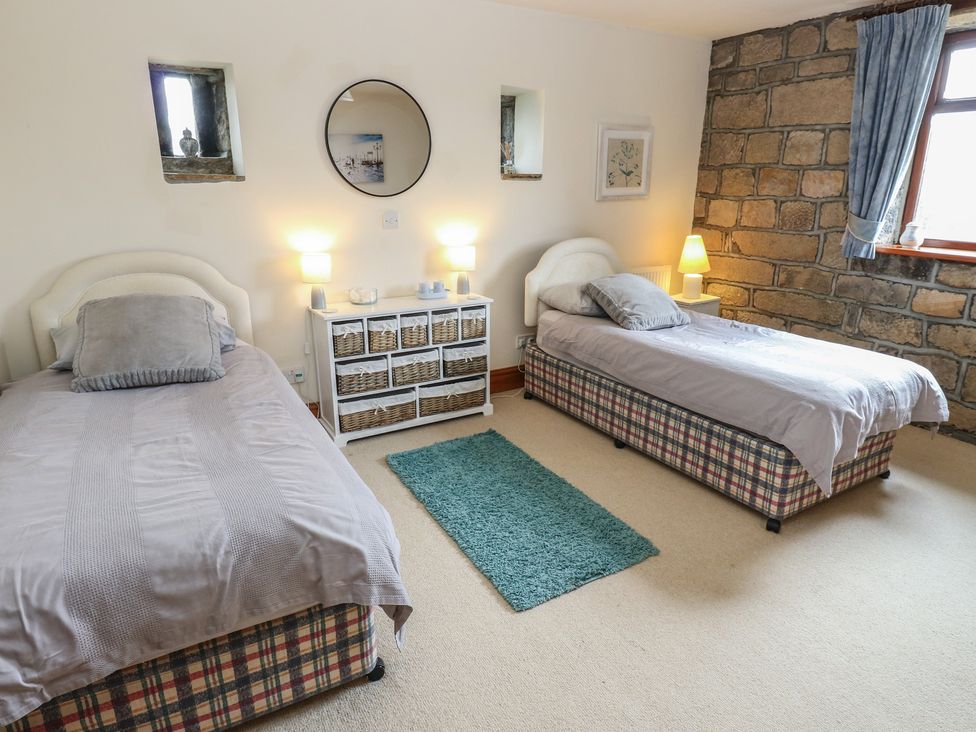 A bedroom with two beds and a storage unit at Shoebroad Barn in Todmorden