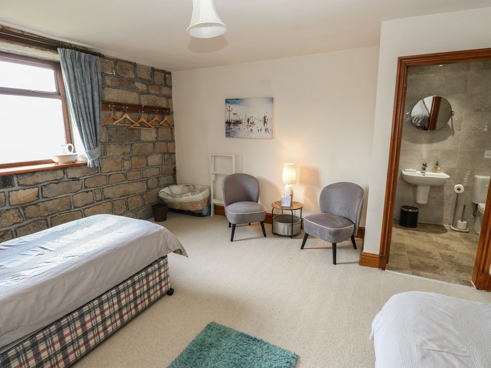 A bedroom with a bed and two armchairs at Shoebroad Barn in Todmorden