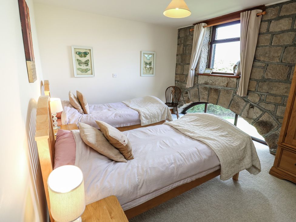 A bedroom with two beds and stone wall at Shoebroad Barn in Todmorden