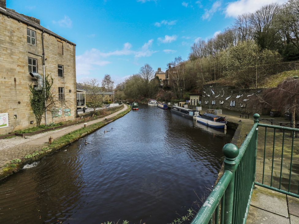 A canal with boats and boathouses at Shoebroad Barn in Todmorden