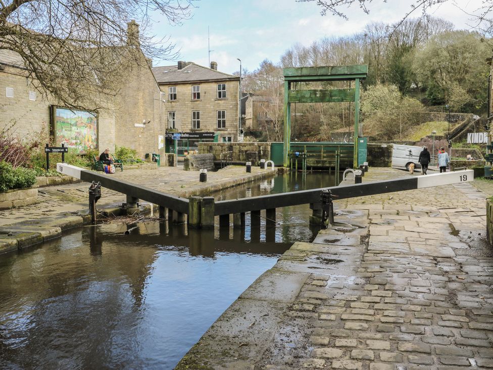A canal lock with a pathway and buildings nearby at Shoebroad Barn Todmorden