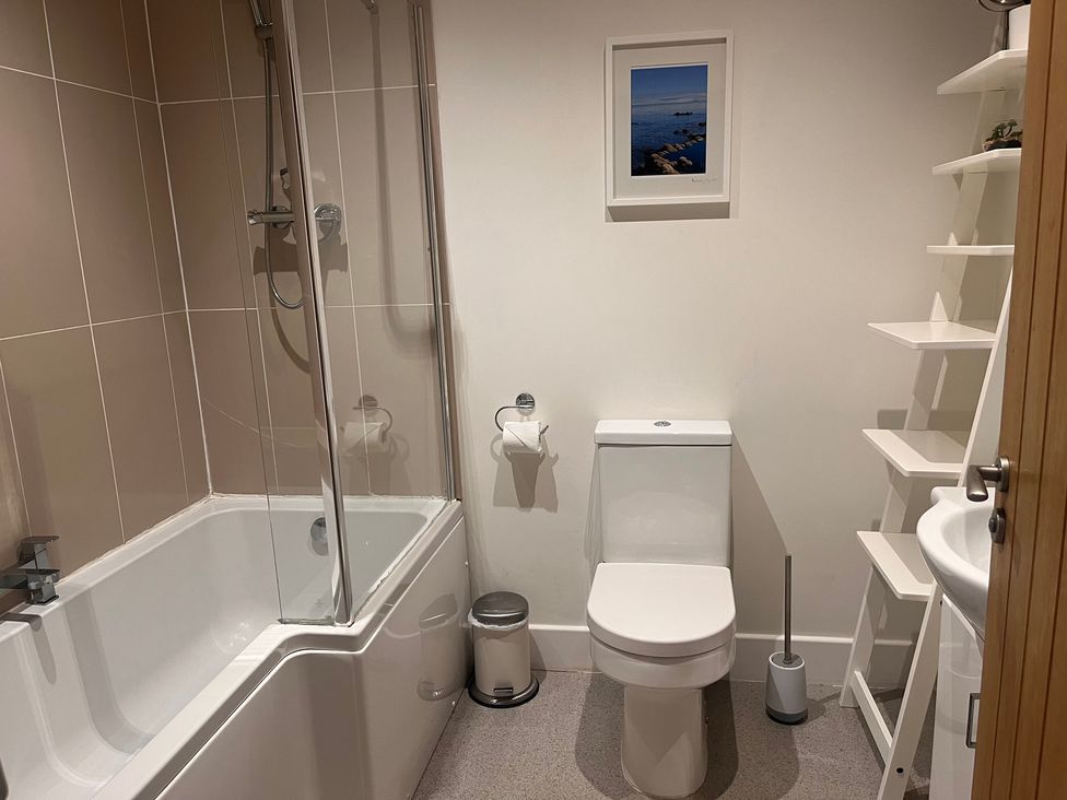 A bathroom with a shower over a bathtub, toilet, and sink at Cherrywood Manor in Bodmin