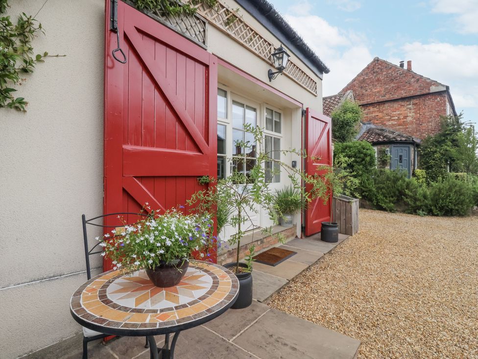 An outdoor area with red doors and a table at The Farmhouse Kitchen in Ripon