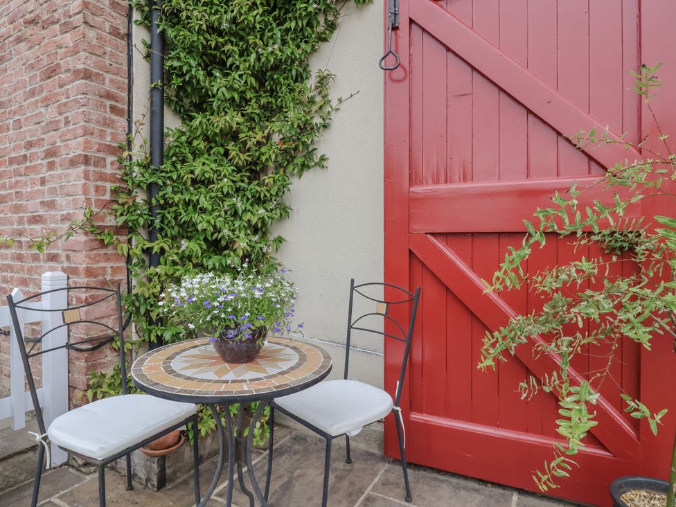 A table and chairs beside a red door at The Farmhouse Kitchen in Ripon