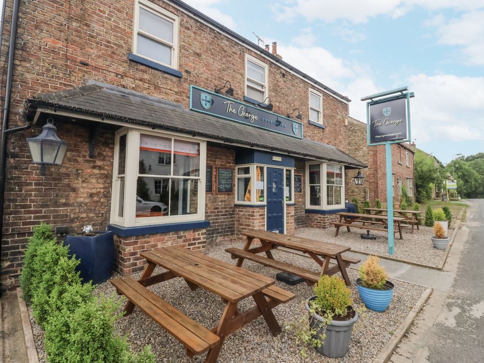 An exterior view of a pub with benches and planters at The George in Unspecified Location