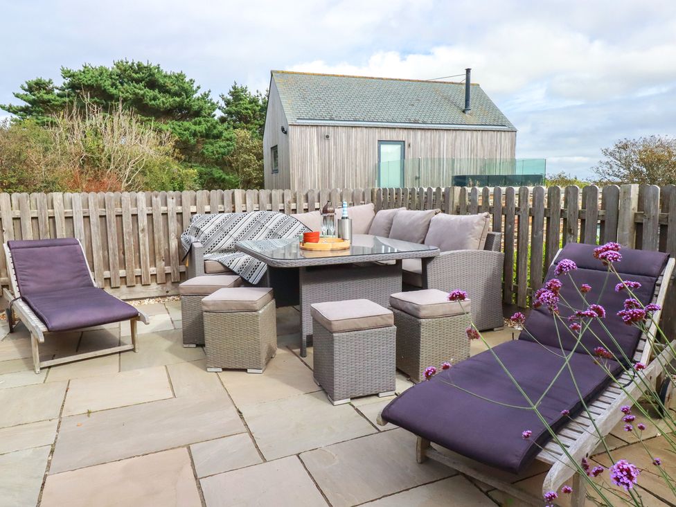 An outdoor seating area with a table and lounge chairs at Idlewild, 2 Wheal Turnavore St Agnes