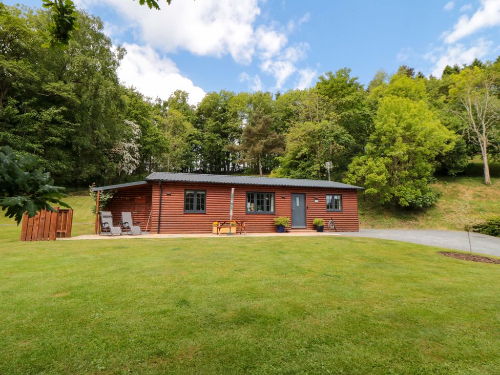 A wooden cabin with chairs and grass area at Ryedale Country Lodges - Hazel Lodge Kirkbymoorside