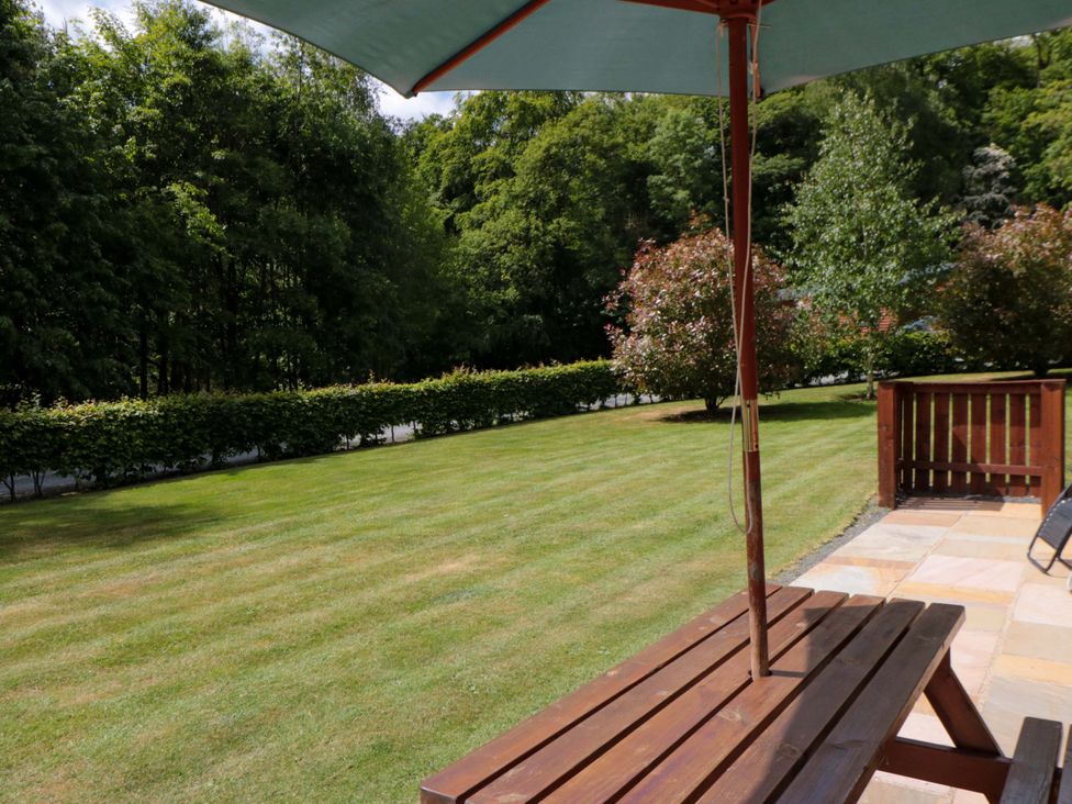 A garden with a table and parasol at Ryedale Country Lodges - Willow Lodge Kirkbymoorside