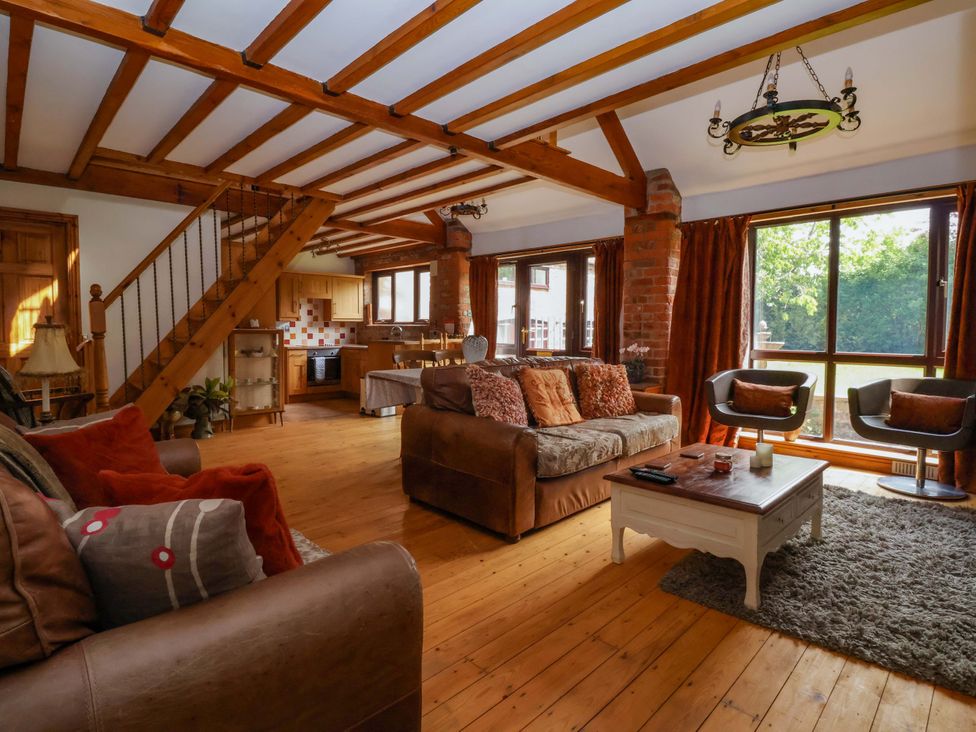 A living room with a sofa, coffee table, and staircase at The Stables (2 bed) Driffield