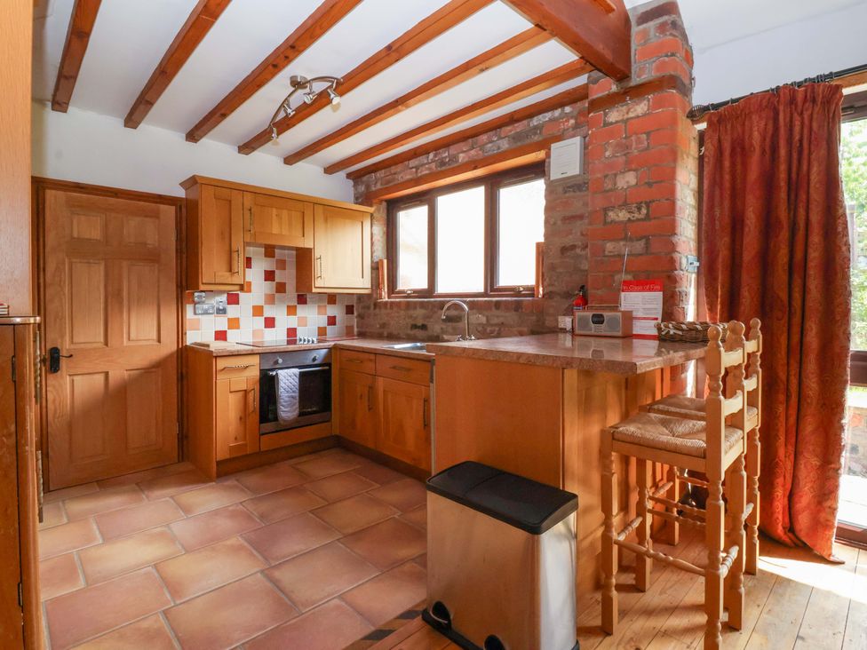 A kitchen with wooden cabinets and a dining area at The Stables (2 bed) Driffield