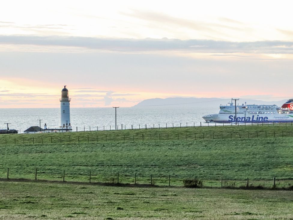 A lighthouse and a ferry on the ocean at Corsewall Castle Farm Lodges in Kirkcolm