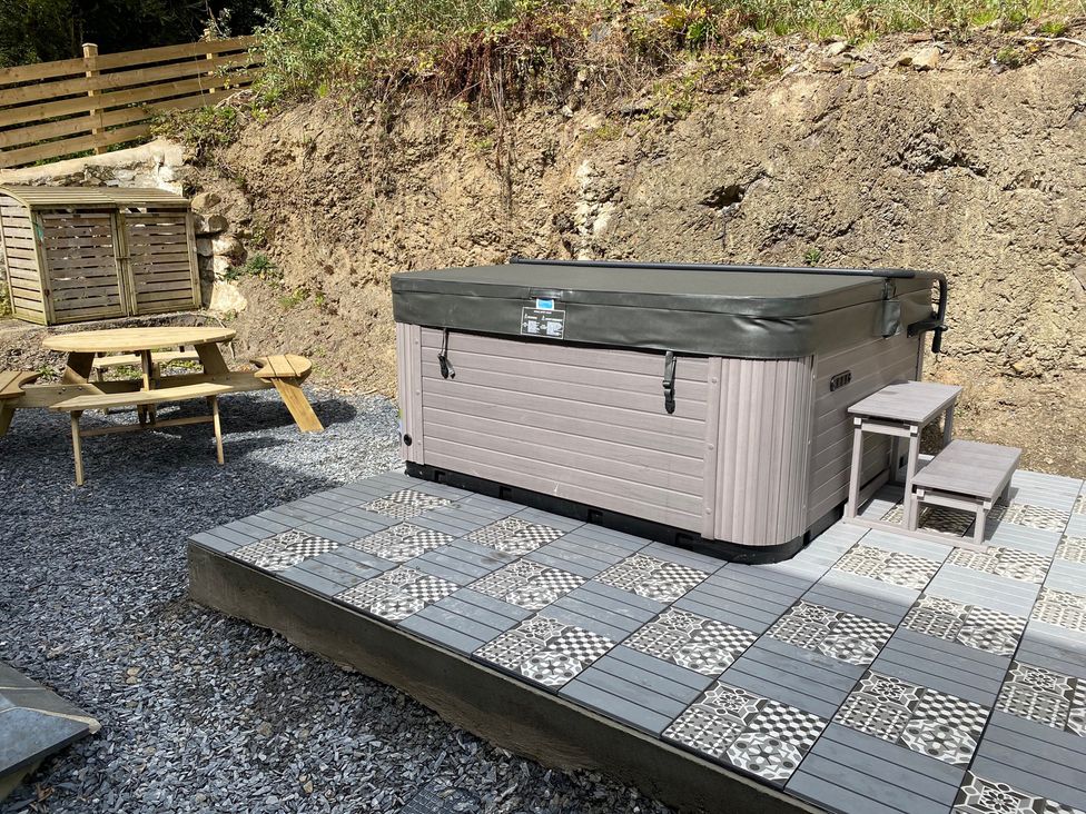 An outdoor area with a hot tub and picnic bench at The Cottage in Llaniestyn