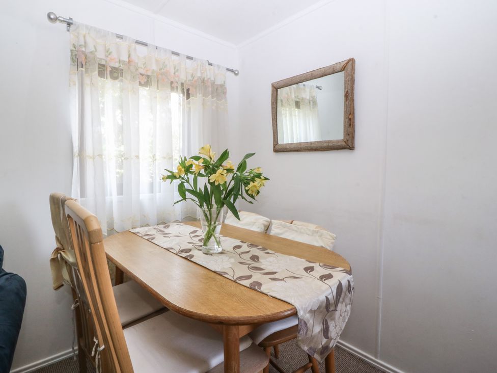 A dining room with a table and chairs at Castell Chalet in Penrhos near Pwllheli