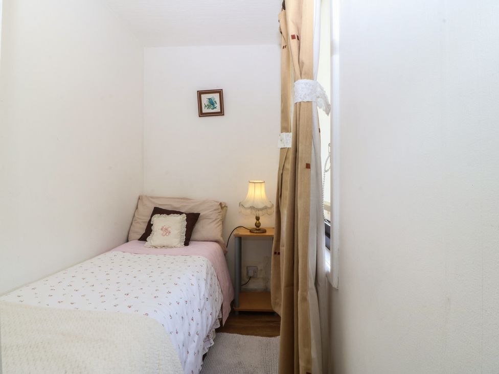 A bedroom with a bed and a lamp at Castell Chalet in Penrhos near Pwllheli