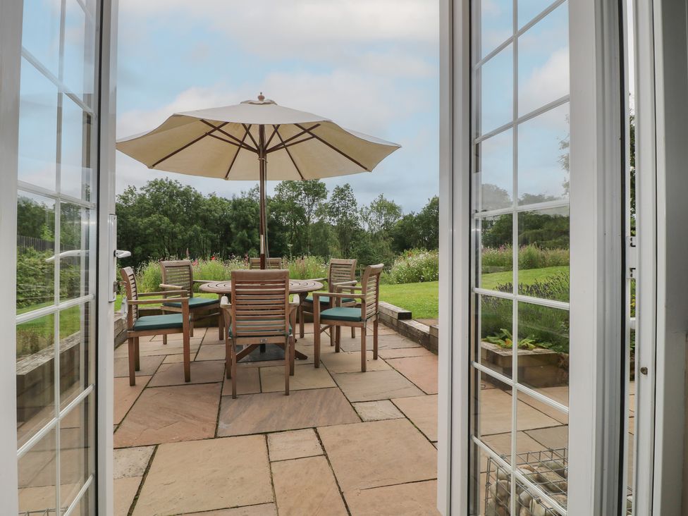 A garden with a table and chairs under a parasol at Ivet Lowe Hopton near Wirksworth