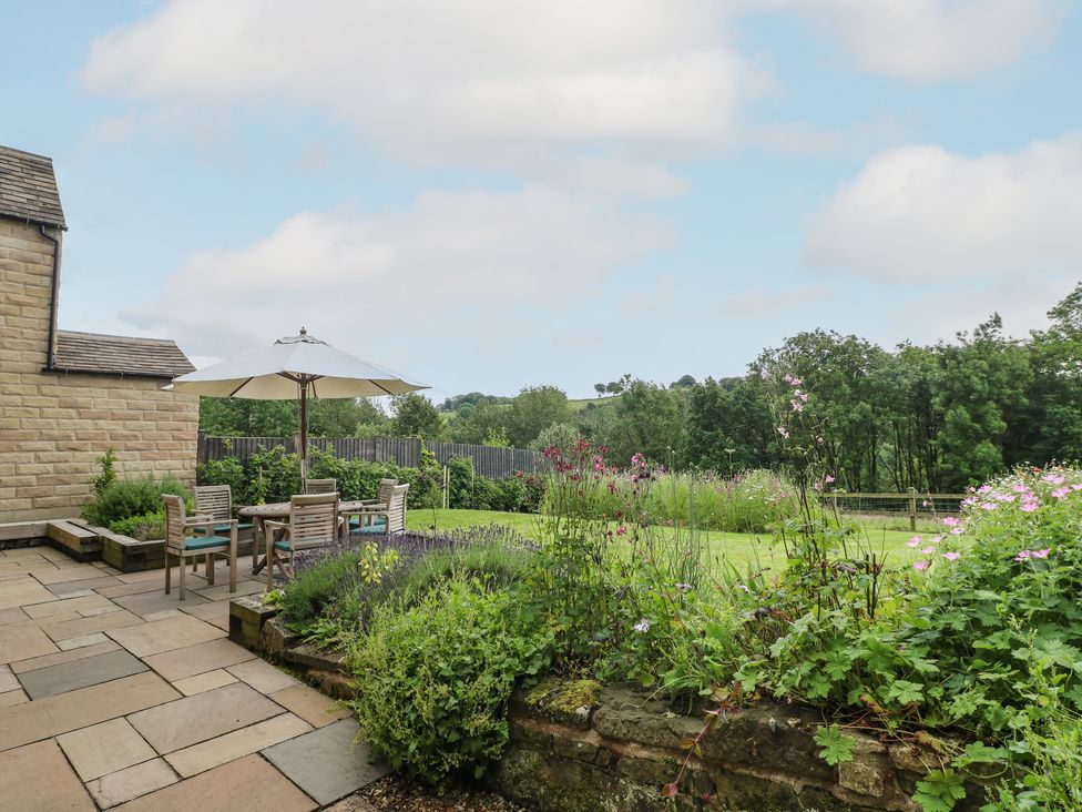 A garden with a table and chairs under an umbrella at Ivet Lowe Hopton near Wirksworth