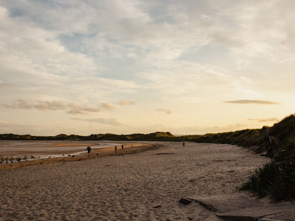 A beach with people walking at Betony in Bamburgh