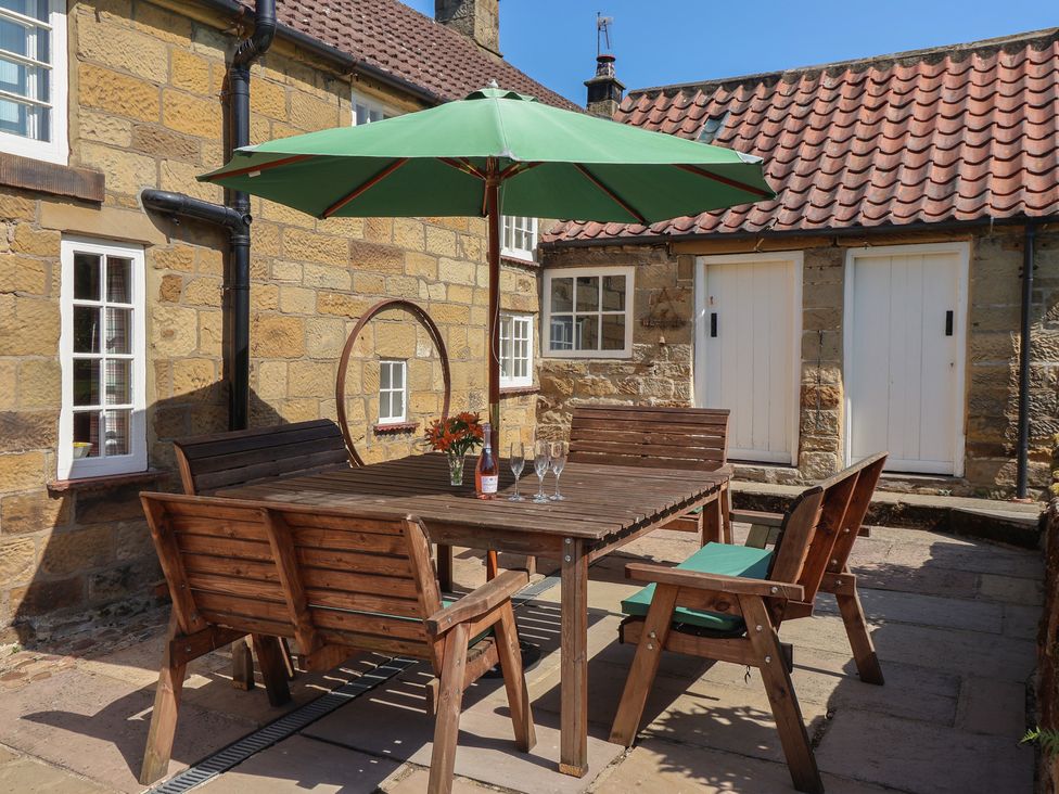 An outdoor patio with a wooden table and chairs at Webstone House Thimbleby near Osmotherley