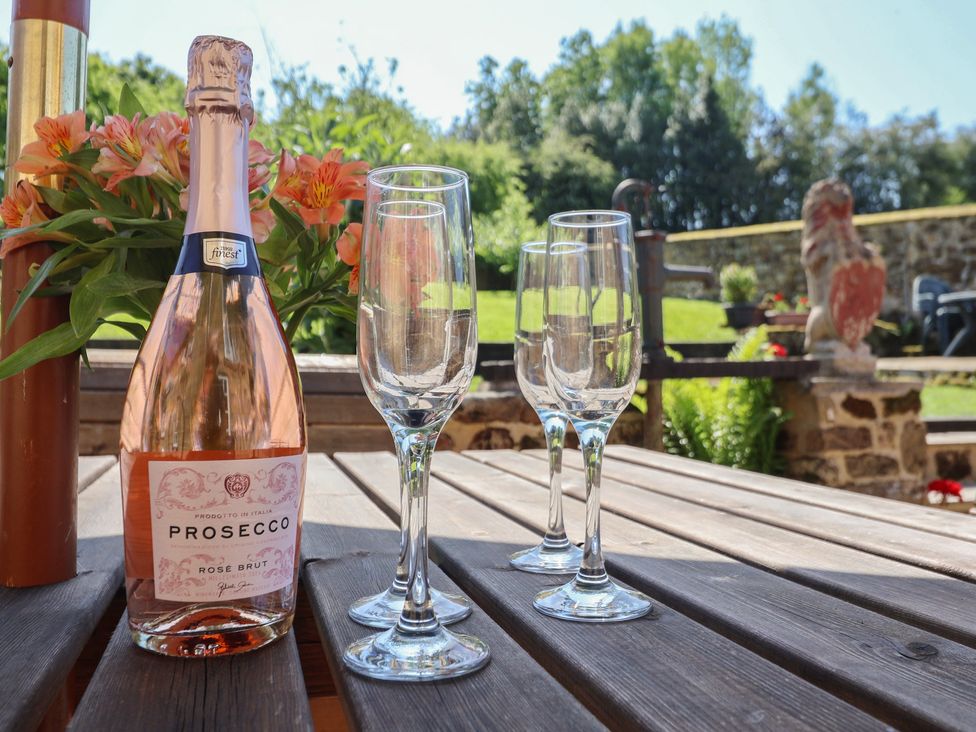 A bottle of Prosecco and wine glasses on a table in an outdoor area at Webstone House Thimbleby near Osmotherley