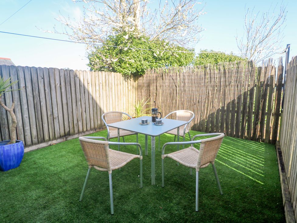 A garden with a table and four chairs at Sunflower Cottage in St Issey
