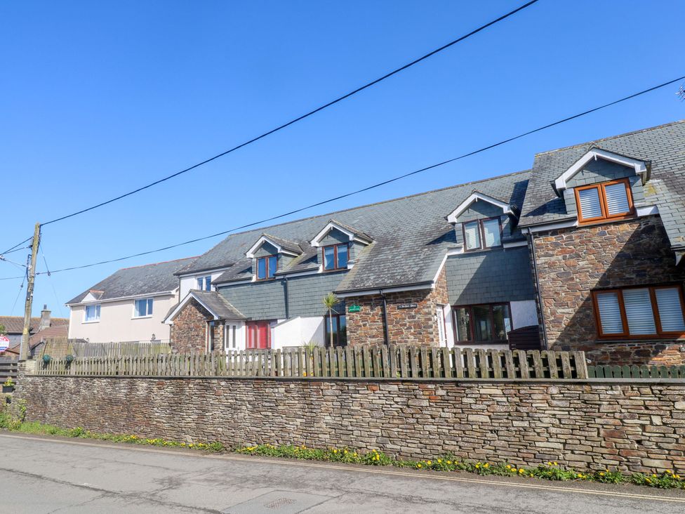 A row of houses with stone walls and a wooden fence at Sunflower Cottage St Issey