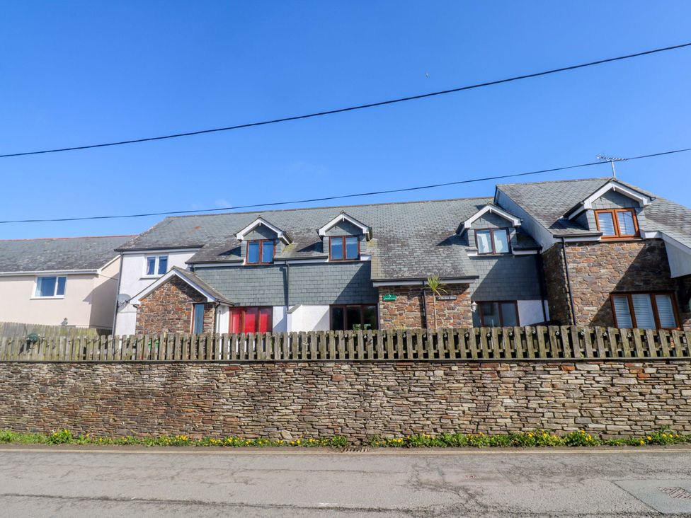 A house with a stone wall and a fence at Sunflower Cottage in St Issey