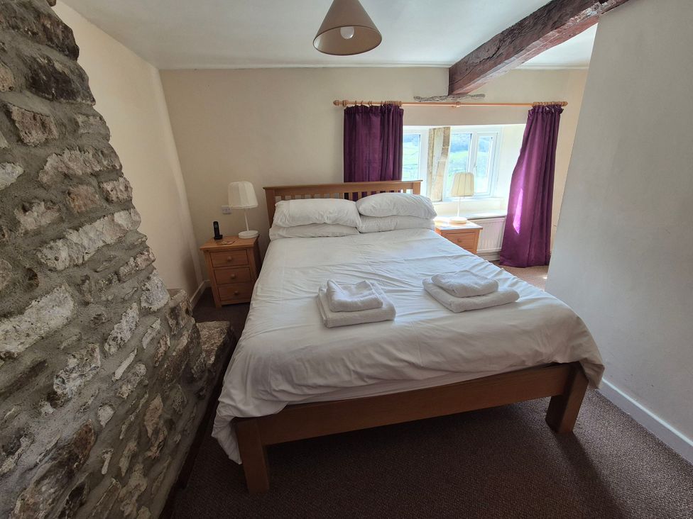 A bedroom with a bed and stone wall at Dale View in Buckden