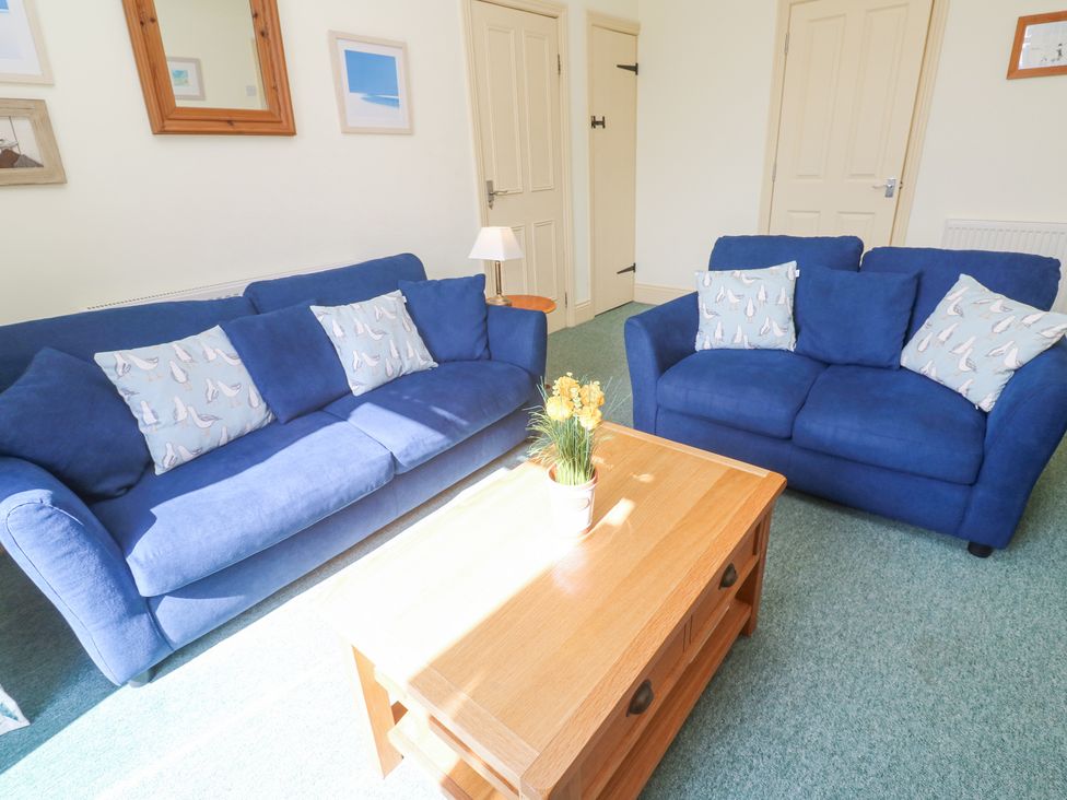 A sitting room with two blue sofas and a wooden coffee table with flowers at Old Chapel Cottage Trescowe near Praa Sands
