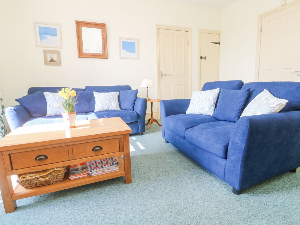 A living room with blue sofas a wooden coffee table with a plant and cushion pillows at Old Chapel Cottage Trescowe near Praa Sands