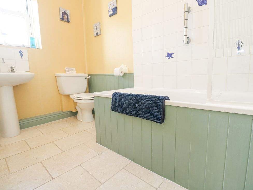 A bathroom with a bathtub a toilet a pedestal sink and a towel on the bathtub at Old Chapel Cottage Trescowe near Praa Sands