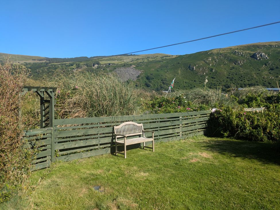 A garden with a bench and a fence at Minydon in Fairbourne