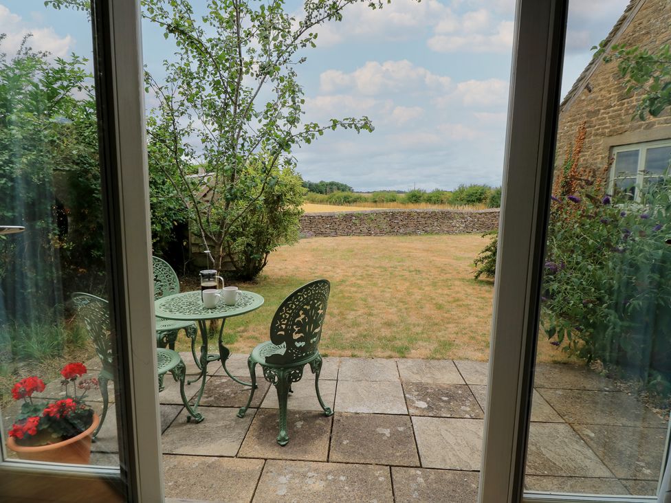 A garden with a table and chairs looking out at the fields at The Lodge at Mortons in Hankerton