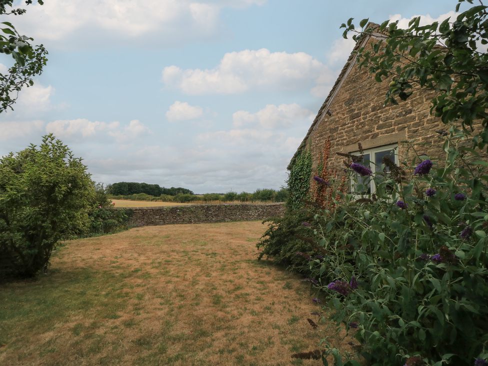 A garden with a stone wall and house at The Lodge at Mortons in Hankerton