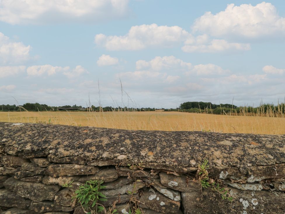 A field with a stone wall and clouds at The Lodge at Mortons Hankerton