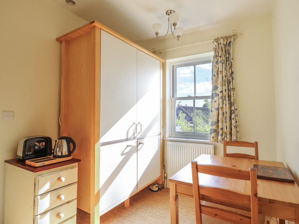 A kitchen with a cupboard, table, and chairs at Over Village Studio in Over