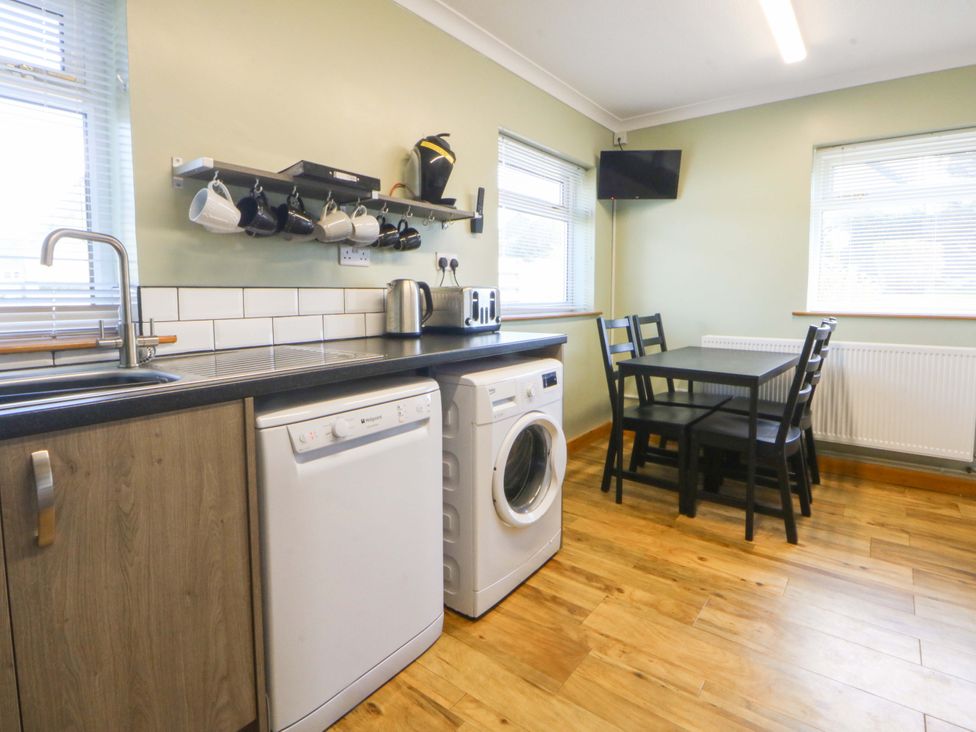 A kitchen with appliances and a dining table at Pen Y Garth in Mynytho near Llanbedrog