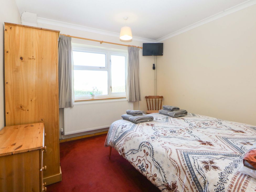 A bedroom with bed and wardrobe at Pen Y Garth in Mynytho near Llanbedrog