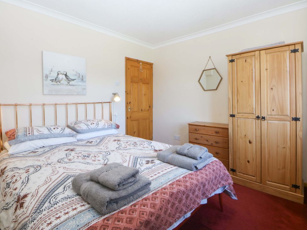A bedroom with a bed and wardrobe at Pen Y Garth Mynytho near Llanbedrog