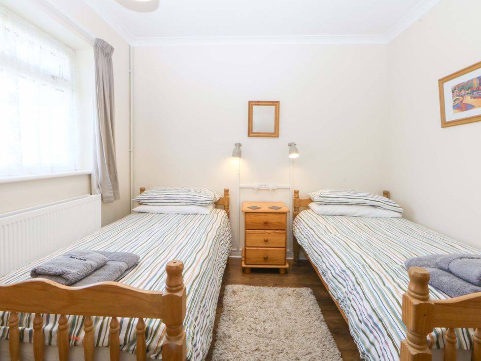 A bedroom with two single beds and a bedside table at Pen Y Garth in Mynytho near Llanbedrog