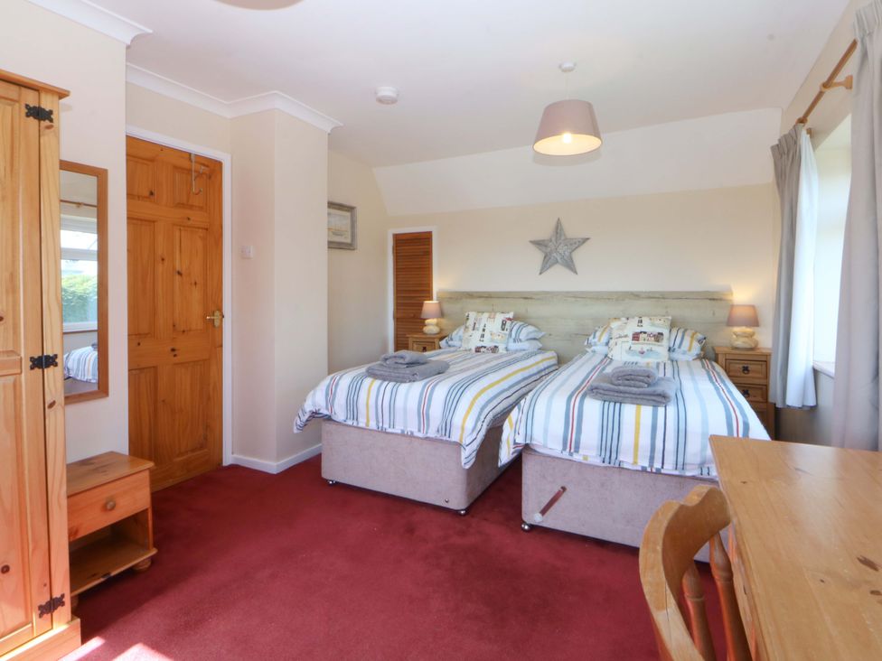 A bedroom with two beds and a dresser at Pen Y Garth Mynytho near Llanbedrog